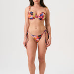 Bikini sostenible Gara Calei. Top con aros y tirantes ajustables, braga normal con lazadas. Tejido reciclado ECOWAVE® con estampado tie-dye y acabado lúrex. Hecho en España de forma ética.