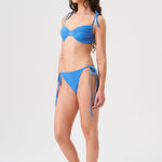 Bikini sostenible Gara Positano, top fruncido con aros y tirantes ajustables. Braga normal con lazadas. Tejido reciclado ECONYL®. Color azul marino inspirado en aguas cristalinas. Acabado atoallado. Hecho en España de forma ética.