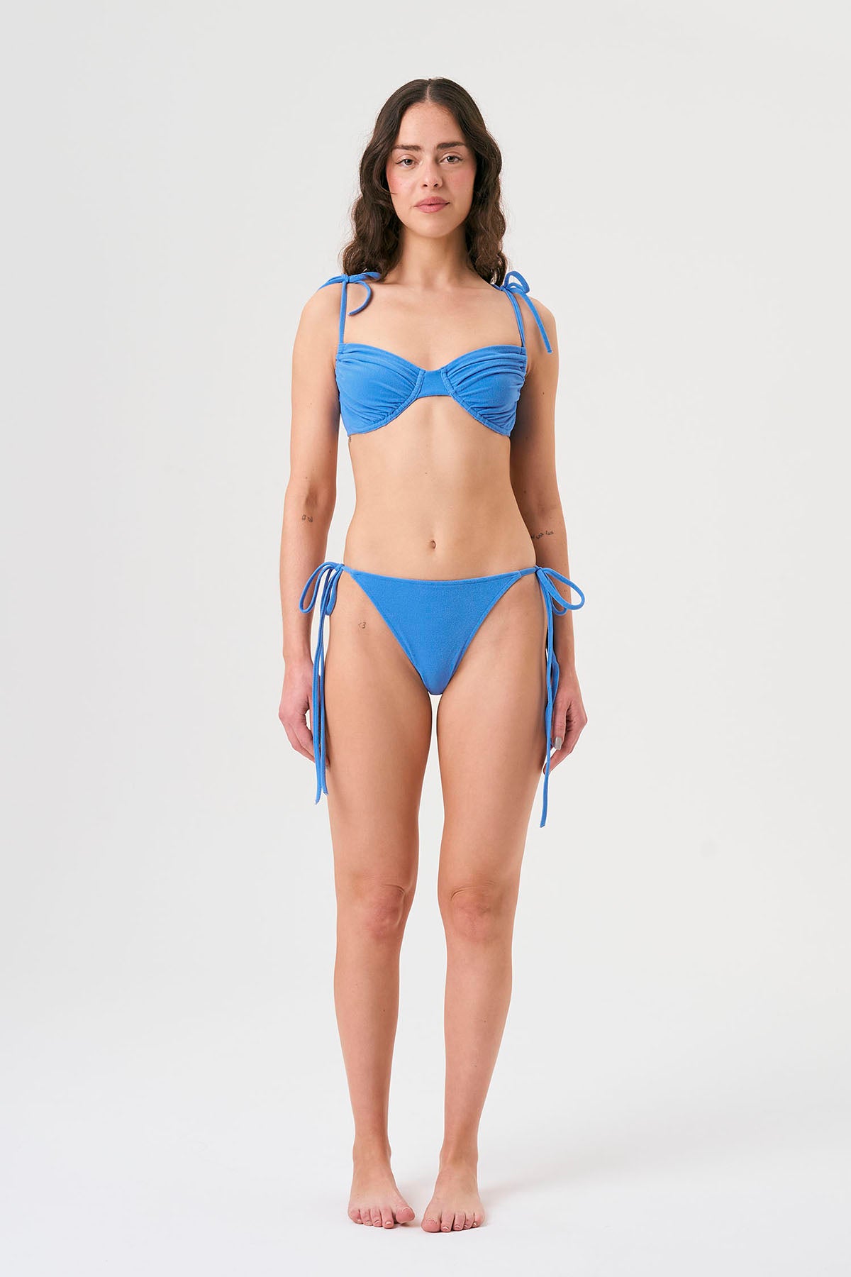 Bikini sostenible Gara Positano, top fruncido con aros y tirantes ajustables. Braga normal con lazadas. Tejido reciclado ECONYL®. Color azul marino inspirado en aguas cristalinas. Acabado atoallado. Hecho en España de forma ética.