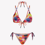 Bikini sostenible Lise Gara Calei. Top triangular multiposición y braga normal con lazada. Tejido ECOWAVE® con estampado tie-dye acuarelado y acabado lúrex. Hecho en España con producción ética.