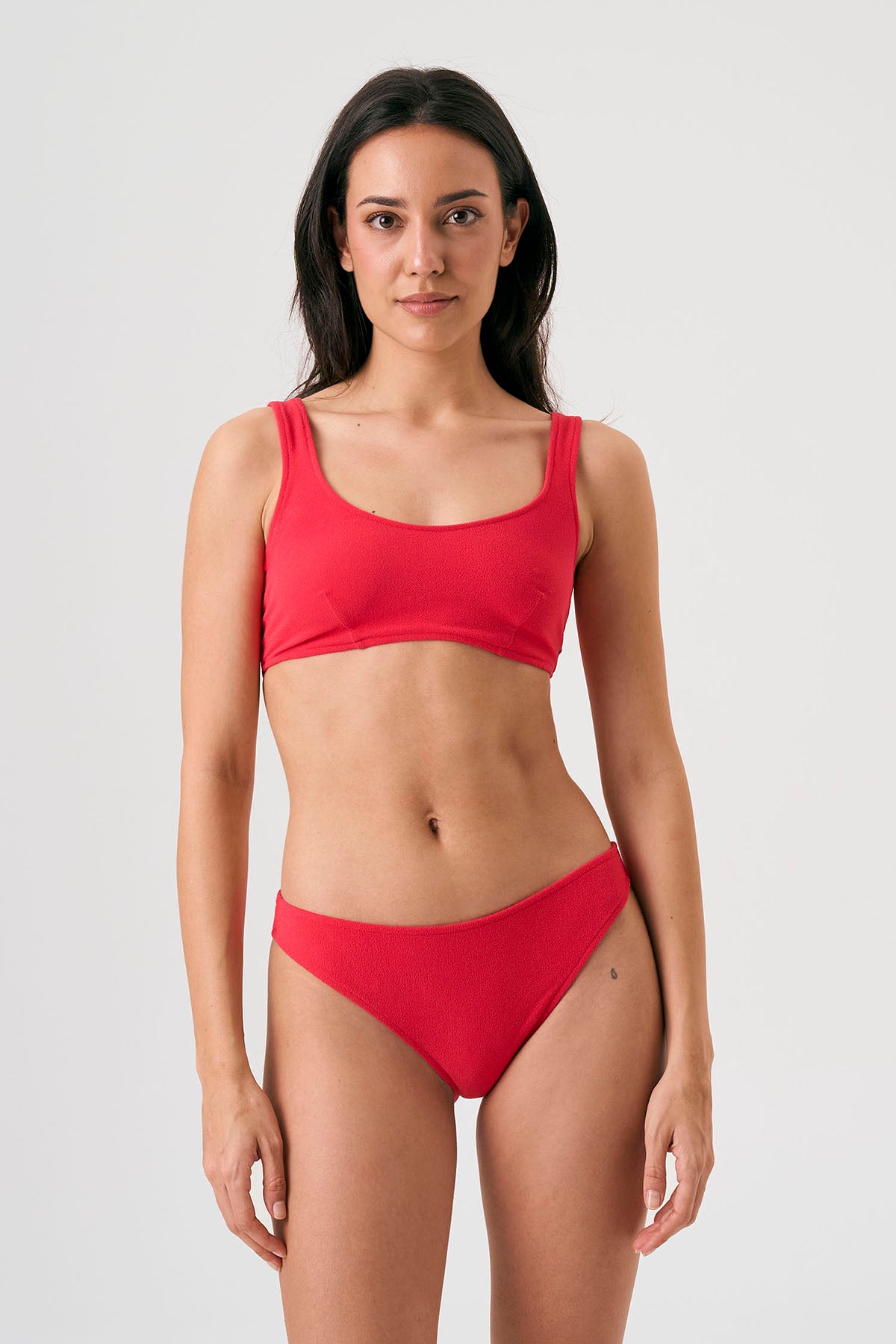 Bikini sostenible Mani Bimba Berry de CIRCU. Top deportivo con tirantes anchos para sujeción y braguita de corte clásico comfort. Tejido reciclado ECONYL® en color rojo cereza con textura atoallada. Hecho artesanalmente en España.