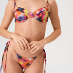 Bikini sostenible Gara Lise Calei. Top con aro y tirantes ajustables, braga tanga con lazadas. Tejido reciclado ECOWAVE® con estampado tie-dye y acabado lúrex. Hecho a mano en España.