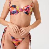 Bikini sostenible Gara Lise Calei. Top con aro y tirantes ajustables, braga tanga con lazadas. Tejido reciclado ECOWAVE® con estampado tie-dye y acabado lúrex. Hecho a mano en España.