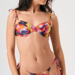 Bikini sostenible Gara Lise Calei. Top con aro y tirantes ajustables, braga tanga con lazadas. Tejido reciclado ECOWAVE® con estampado tie-dye y acabado lúrex. Hecho a mano en España.