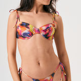 Bikini sostenible Gara Lise Calei. Top con aro y tirantes ajustables, braga tanga con lazadas. Tejido reciclado ECOWAVE® con estampado tie-dye y acabado lúrex. Hecho a mano en España.