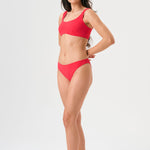 Bikini sostenible Mani Bimba Berry de CIRCU. Top deportivo con tirantes anchos para sujeción y braguita de corte clásico comfort. Tejido reciclado ECONYL® en color rojo cereza con textura atoallada. Hecho artesanalmente en España.
