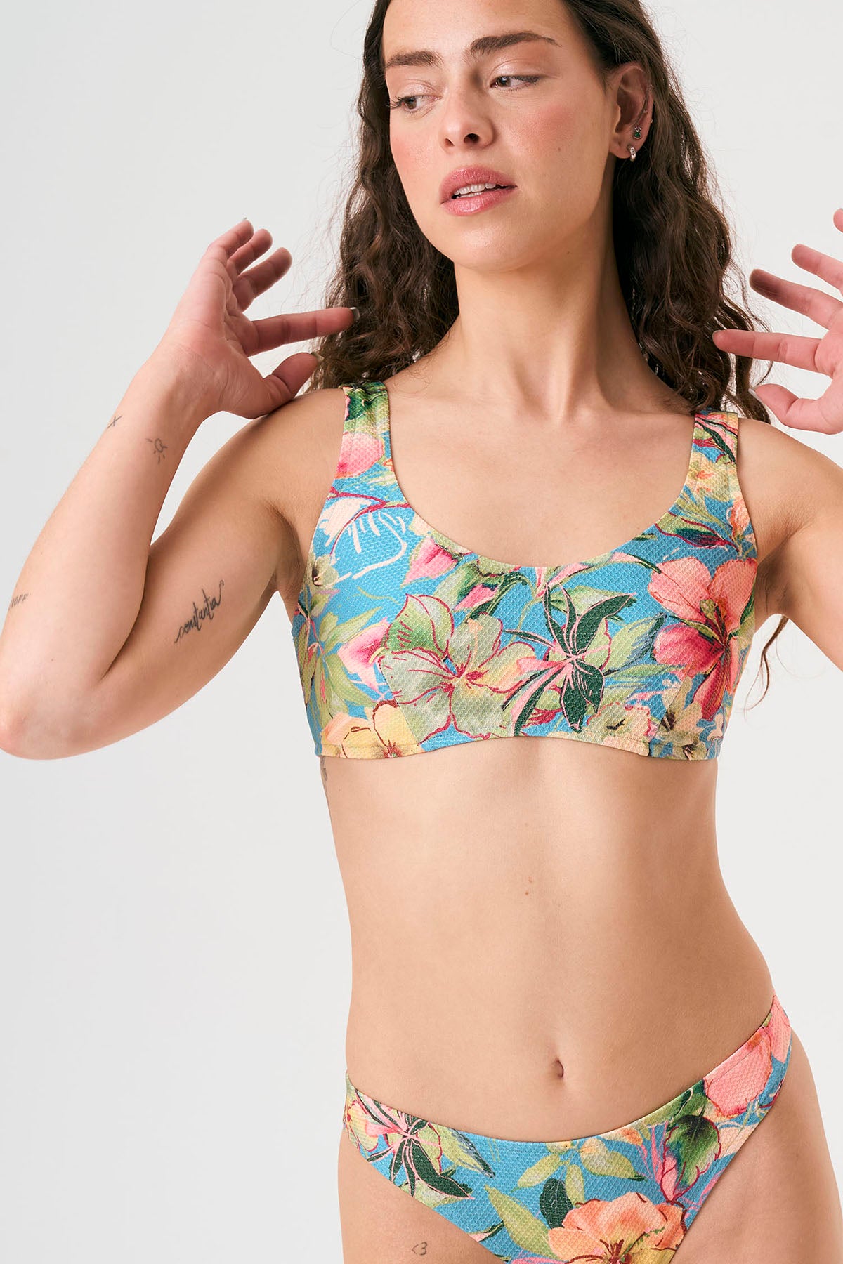 Bikini sostenible deportivo Mani Aloa. Tejido reciclado ECOWAVE® y estampado ZEROWATER. Top deportivo con tirantes anchos y braga brasileña. Print floral en textura piqué con acabado lúrex. Hecho éticamente en España.