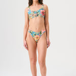 Bikini sostenible deportivo Mani Aloa. Tejido reciclado ECOWAVE® y estampado ZEROWATER. Top deportivo con tirantes anchos y braga brasileña. Print floral en textura piqué con acabado lúrex. Hecho éticamente en España.