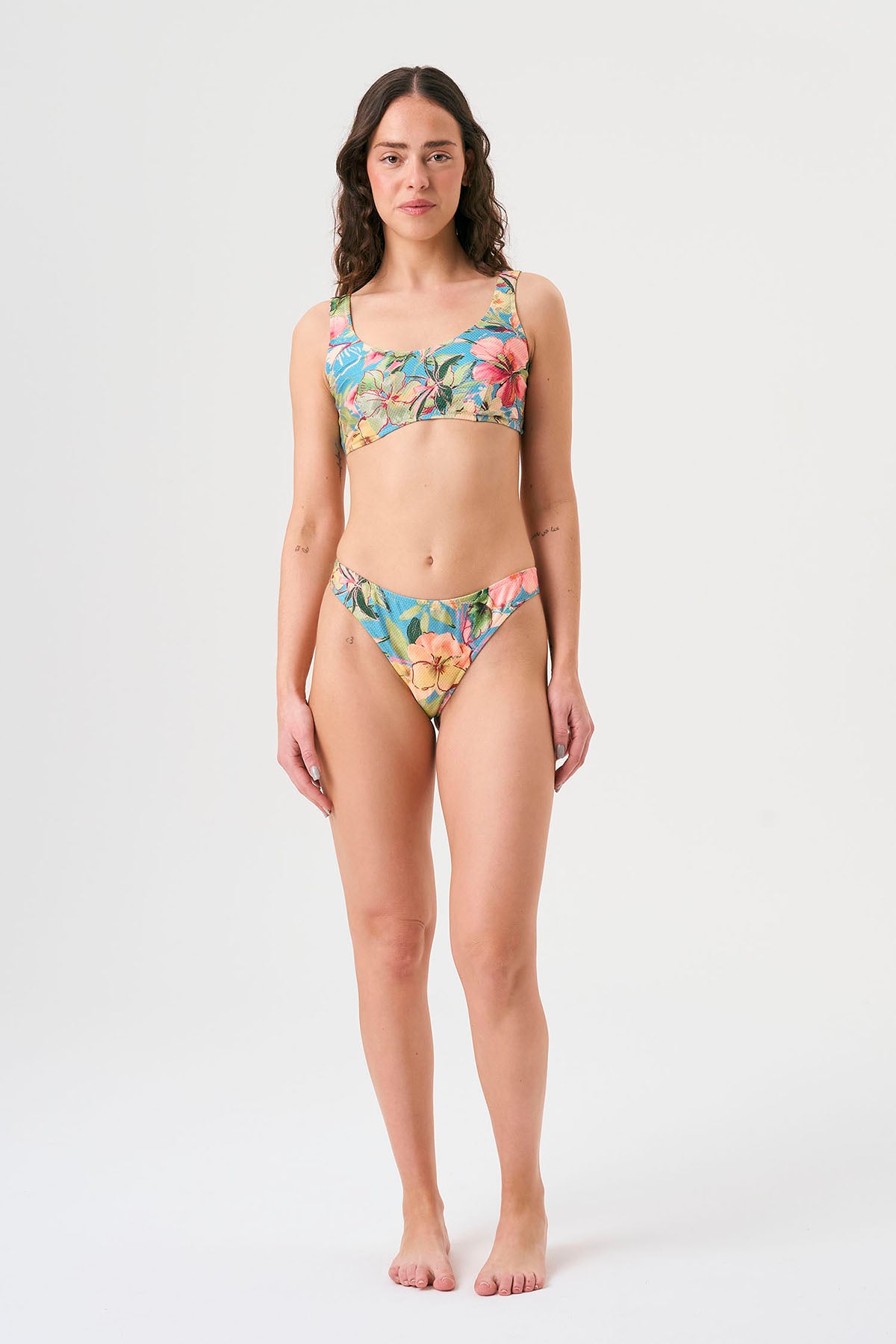 Bikini sostenible deportivo Mani Aloa. Tejido reciclado ECOWAVE® y estampado ZEROWATER. Top deportivo con tirantes anchos y braga brasileña. Print floral en textura piqué con acabado lúrex. Hecho éticamente en España.
