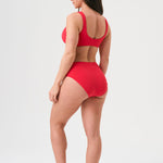Bikini sostenible deportivo Mani Bimba Berry High. Top deportivo con tirantes anchos y braguita alta. Tejido reciclado ECONYL®. Color rojo cereza con textura atoallada. Hecho en España de forma ética. Ideal para máximo confort y sujeción.