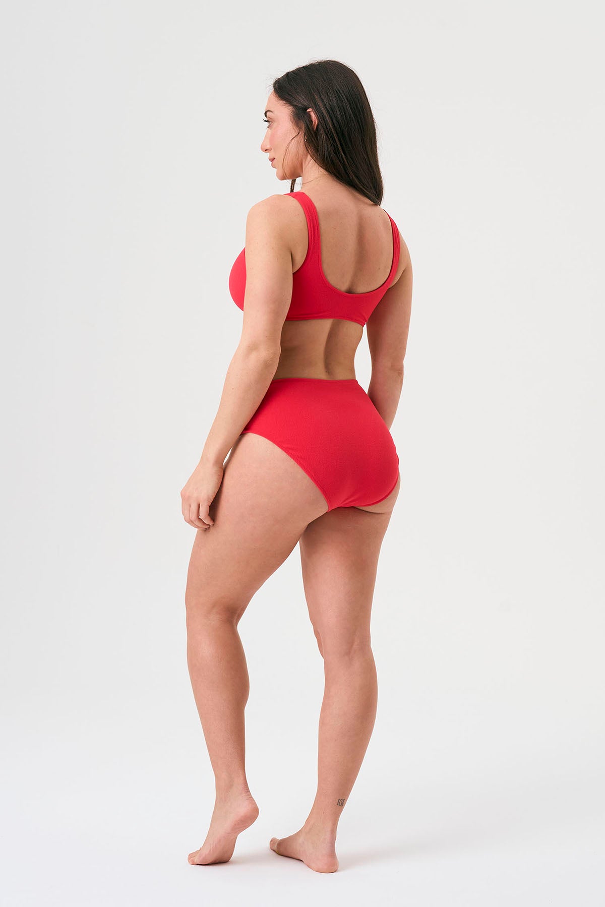 Bikini sostenible deportivo Mani Bimba Berry High. Top deportivo con tirantes anchos y braguita alta. Tejido reciclado ECONYL®. Color rojo cereza con textura atoallada. Hecho en España de forma ética. Ideal para máximo confort y sujeción.