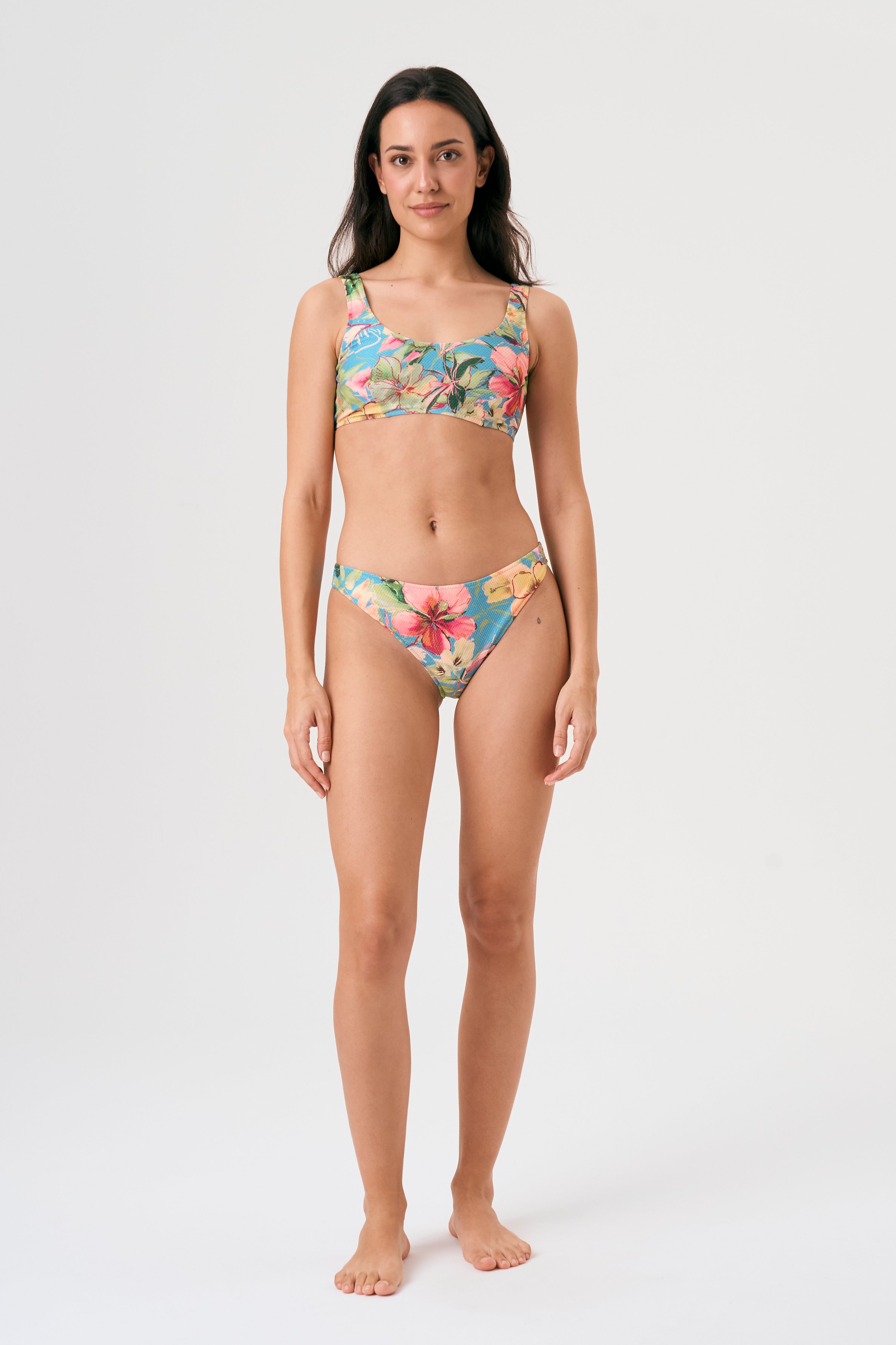 Bikini sostenible deportivo Mani Bimba Aloa. Top con tirantes anchos y sujeción óptima. Braguita de cobertura normal. Tejido reciclado ECOWAVE® con estampado floral en textura piqué y acabado lúrex. Hecho en España.