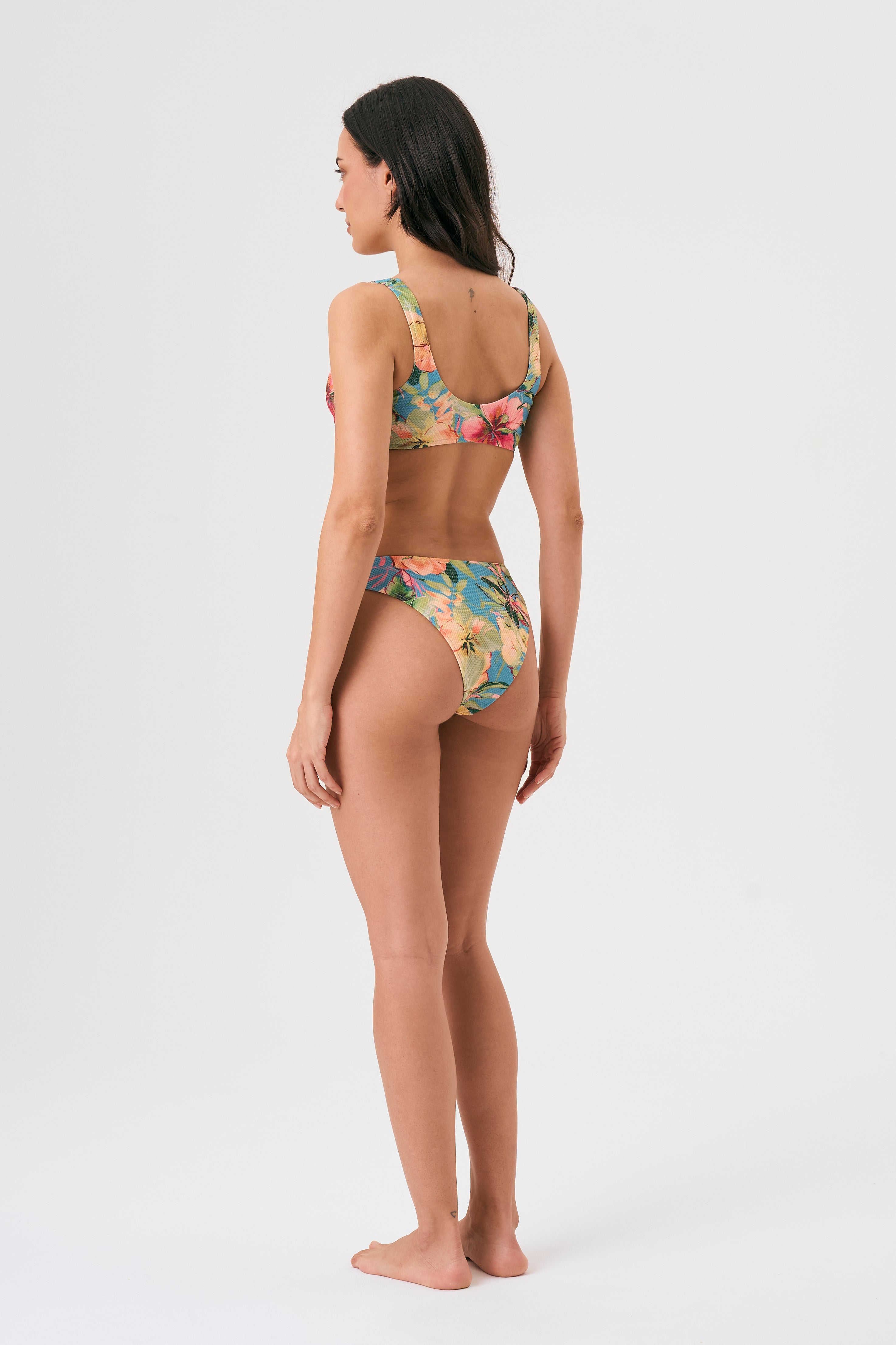 Bikini sostenible deportivo Mani Bimba Aloa. Top con tirantes anchos y sujeción óptima. Braguita de cobertura normal. Tejido reciclado ECOWAVE® con estampado floral en textura piqué y acabado lúrex. Hecho en España.