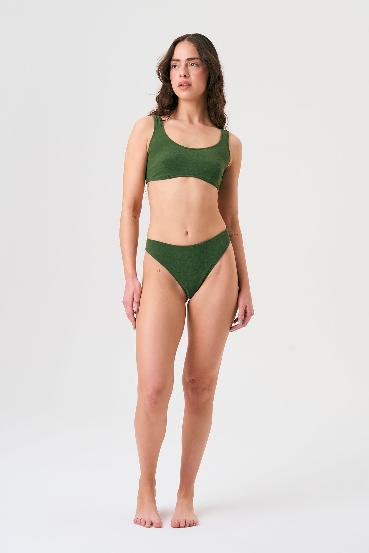 Bikini sostenible Mani Bimba Palm de CIRCU. Top deportivo con tiras anchas y opción de copas, y braga de cobertura normal. Tejido reciclado 100% ECONYL® en verde oscuro mediterráneo con textura atoallada. Hecho artesanalmente en España.