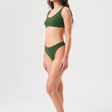 Bikini sostenible Mani Bimba Palm de CIRCU. Top deportivo con tiras anchas y opción de copas, y braga de cobertura normal. Tejido reciclado 100% ECONYL® en verde oscuro mediterráneo con textura atoallada. Hecho artesanalmente en España.