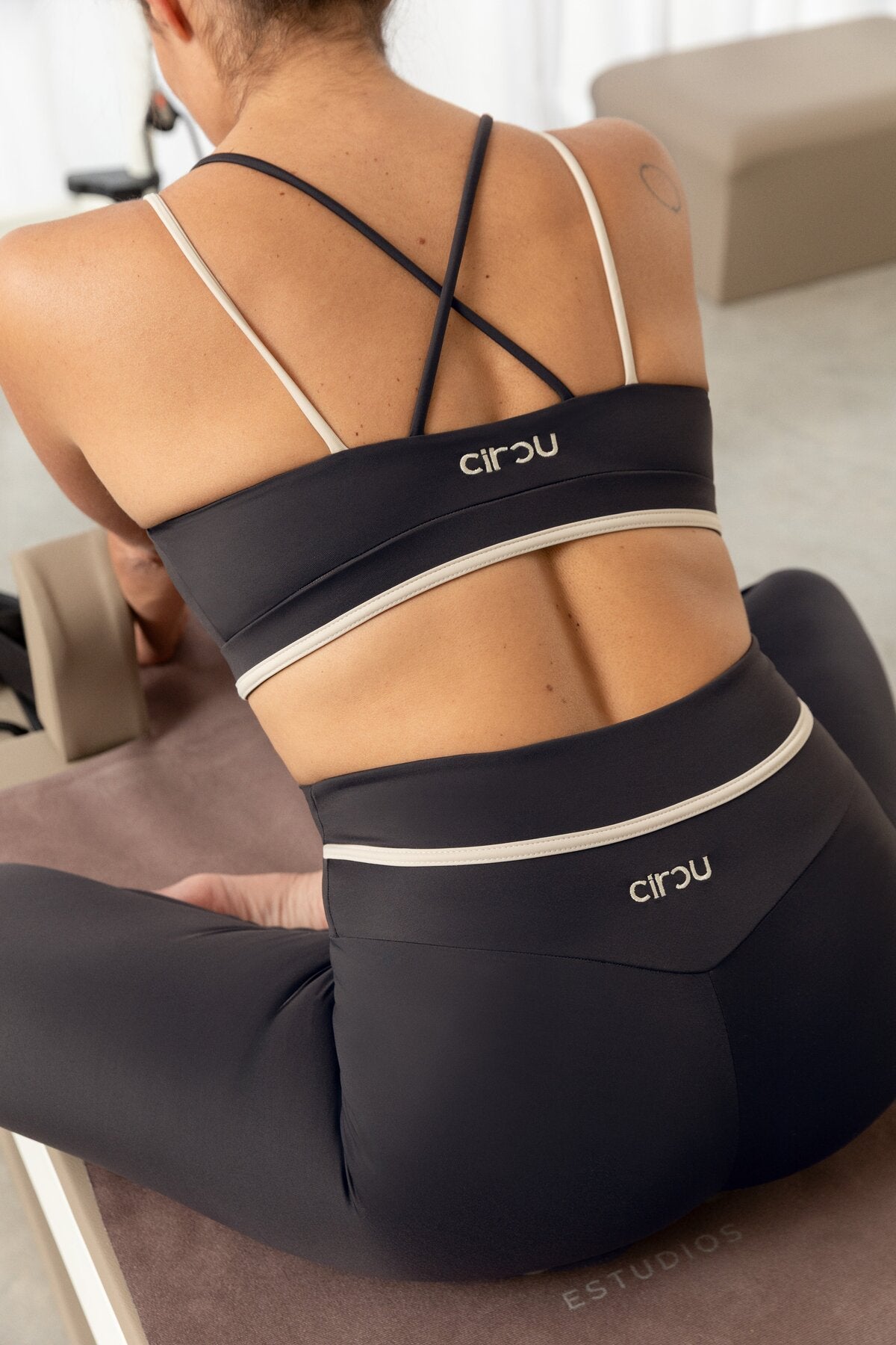 Conjunto deportivo sostenible Sira Grey - modelo de espaldas con tirantes cruzados y logo CIRCU Active Club